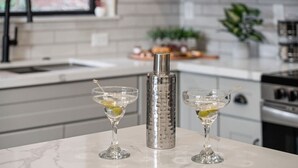 Una cocina con encimera de mármol, dos copas de martini con aceitunas y un coctelero.