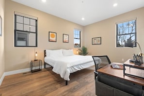 Une chambre à coucher comprenant un lit, un bureau, une chaise, une lampe et des œuvres d’art encadrées accrochées aux murs.
