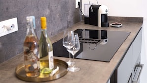A modern kitchen with a built-in induction cooktop, a coffee maker, and wine bottles on a tray. - Appartamento Guglielmo (Oristano)