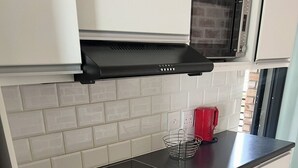 A compact kitchen with a black induction cooktop, a built-in oven, and a microwave above it.