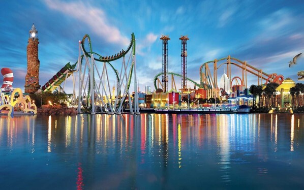 A theme park with various roller coasters and attractions, including a tall tower and a large, illuminated sign.