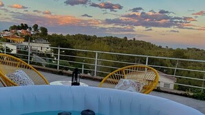An inflatable pool with lounge chairs, a railing, and a view of a hillside with buildings.