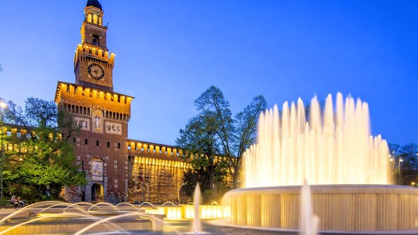 A historic building with a clock tower and a fountain.