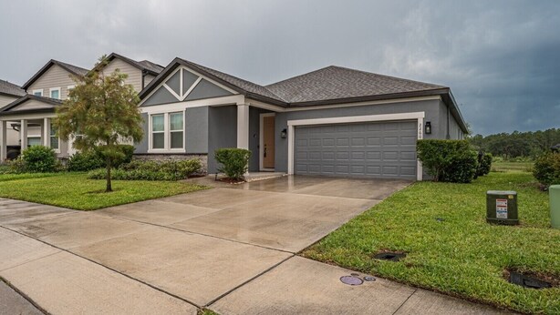 A residential house with a garage, a driveway, and a well-maintained lawn. - New Build - Cozy House & Game Room (Davenport)