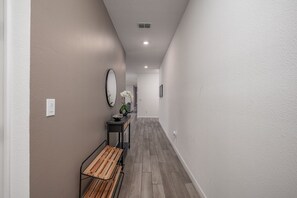 A hallway with a bench, a mirror, and a vase with flowers. - New Build - Cozy House & Game Room (Davenport)