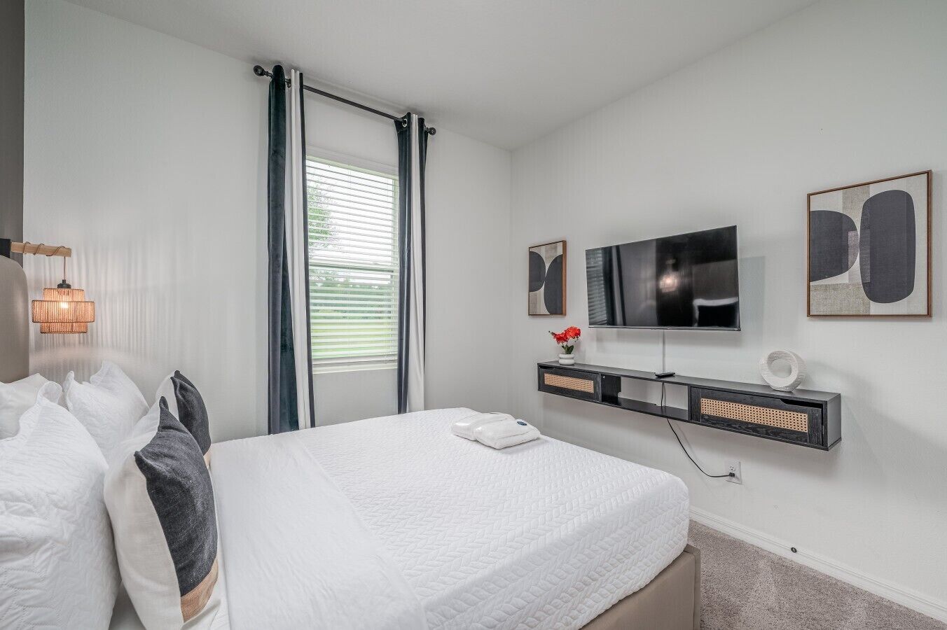 A modern bedroom with a bed, a TV, and artwork on the wall.