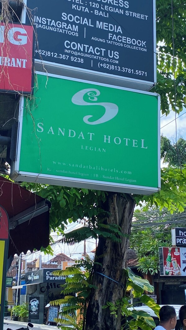 A sign for Sandat Hotel in Legian, Bali, with contact information and social media details.