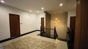 A hallway with a patterned carpet, wooden doors, and a staircase with a railing. - Pepitu Dormitory By Sandat (Legian)