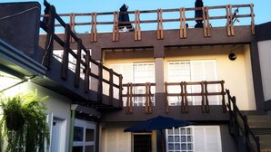 A two-story building with a wooden balcony, a garage door, and a bicycle parked outside. - Pousada da Pedra do Mar (Matinhos)