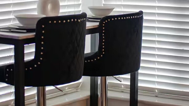 Una mesa de comedor con dos sillas, un jarrón con plantas secas y un bol.