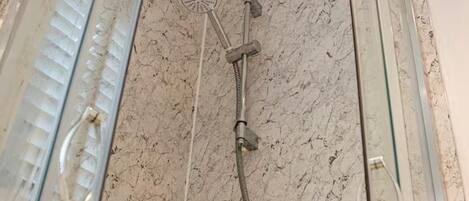 A glass-enclosed shower with a handheld showerhead and a flexible hose.