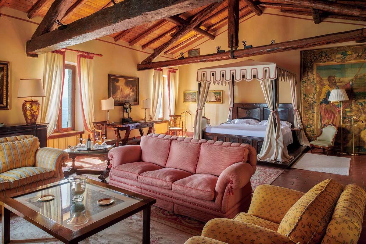 A traditional room with a four-poster bed, a sofa, and a coffee table.