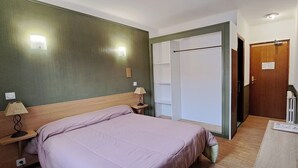 Una camera da letto con un letto in legno, due lampade sui comodini, una luce a parete e una porta con maniglia.
