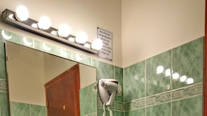 Un bagno con lavandino, specchio e asciugacapelli fissato alla parete.