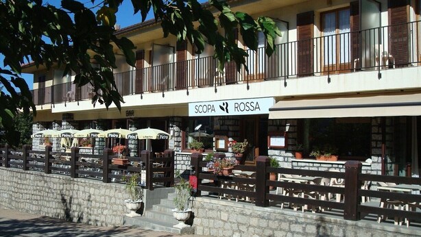 Un ristorante chiamato "SCOPA ROSSA" con posti a sedere all'aperto e piante in vaso.