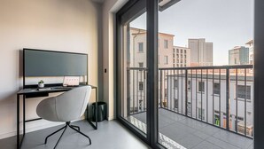 Un apartamento moderno con un ventanal grande, un escritorio con una computadora portátil y una silla.