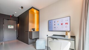 Une chambre d’hôtel moderne équipée d’un bureau, d’une chaise et d’un écran fixé au mur qui affiche les différents services proposés par l’hôtel.