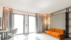 Un salon moderne avec un canapé, un fauteuil, une petite table et une grande fenêtre.