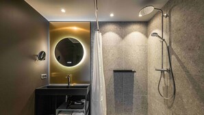 Une salle de bain moderne avec un miroir rond, un lavabo, une douche et un porte-serviettes.