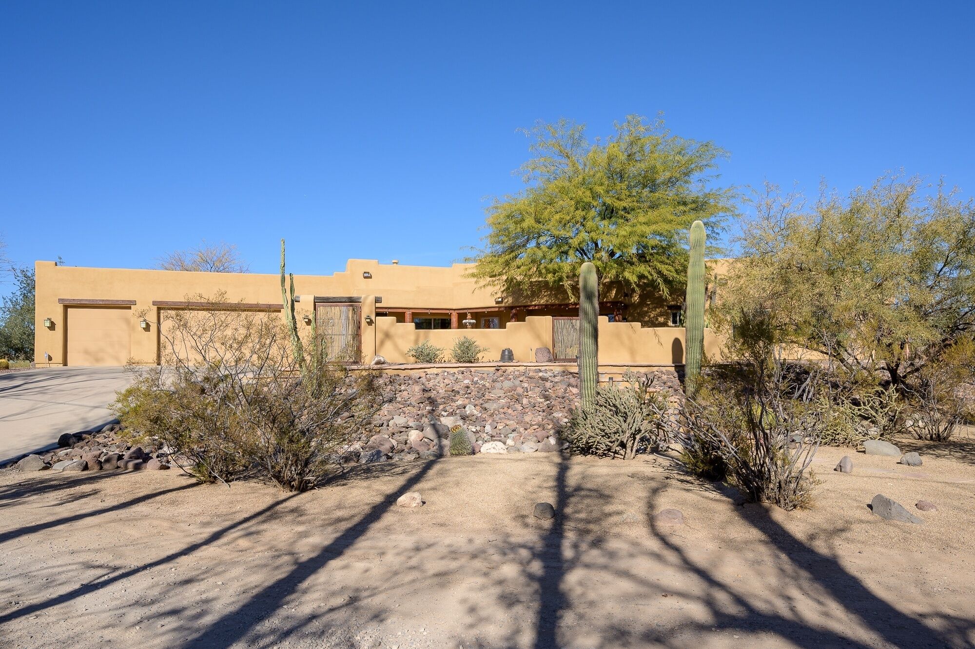A desert-style building with a large garage, surrounded by cacti and sparse vegetation.