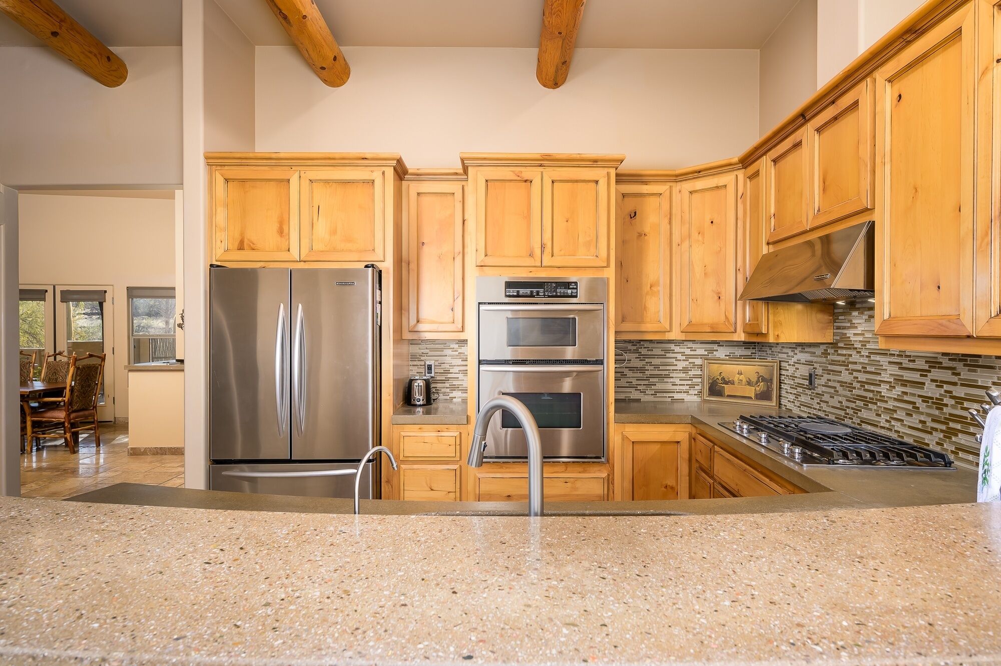 A modern kitchen with wooden cabinets, stainless steel appliances, and a granite countertop.