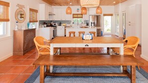 Une cuisine spacieuse dotée d’un îlot central, de meubles blancs et d’un plafond en bois.