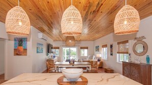 Une pièce spacieuse avec un plafond en bois, une grande table à manger agrémentée d’un centre de table, et des suspensions en osier.