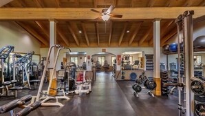 A gym with various exercise equipment, wooden beams on the ceiling, and a ceiling fan. - Timber Creek 309 1 Bedroom Condo (Truckee)