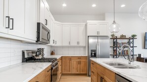 Una cocina moderna con armarios blancos, un refrigerador de acero inoxidable y una encimera de madera.