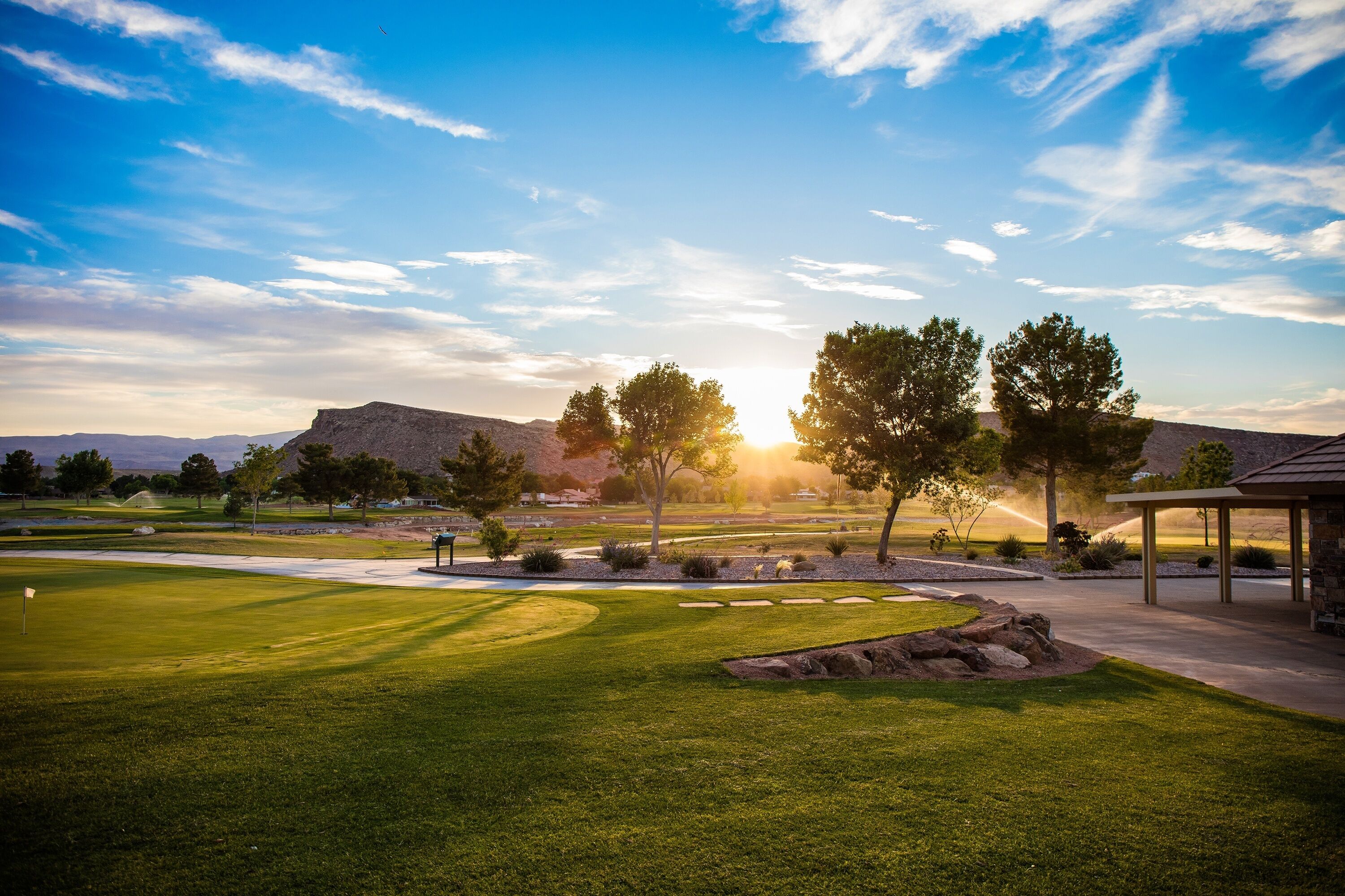 A golf course with a well-maintained lawn, a pavilion, and a mountain in the background.