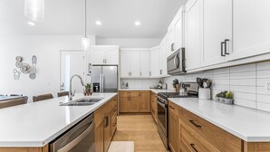 A modern kitchen with white cabinetry, stainless steel appliances, and a central island.