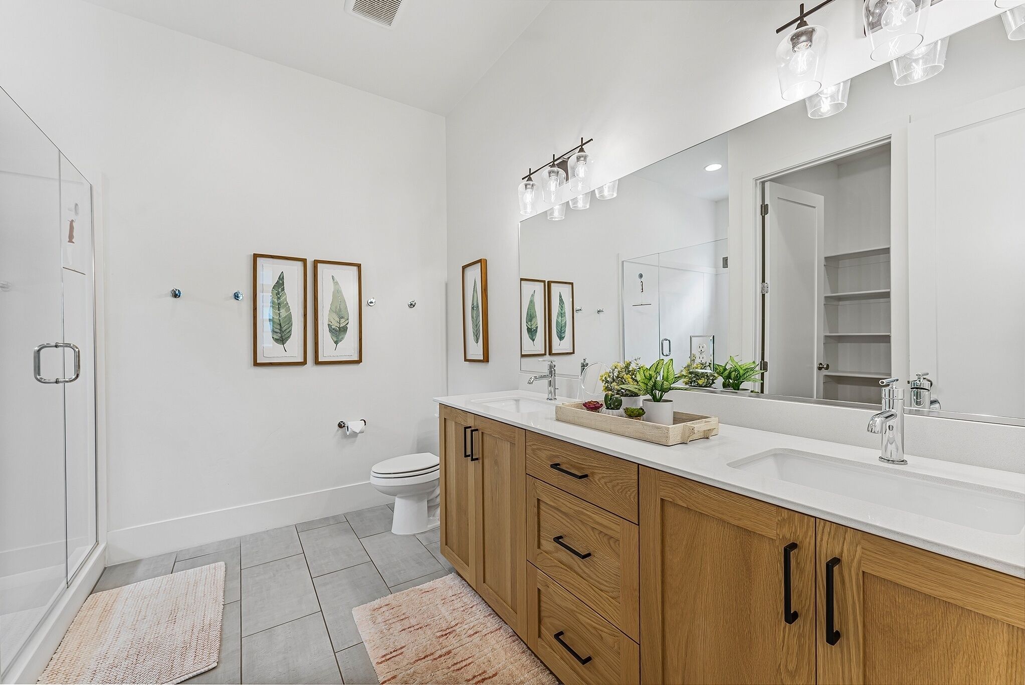 A modern bathroom with a white sink, wooden cabinets, and a large mirror.