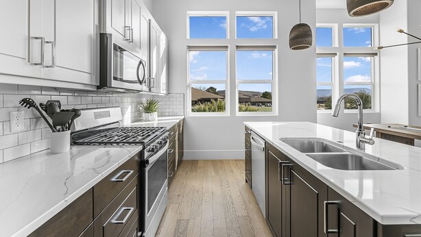 Una cocina moderna con armarios blancos, una estufa de acero inoxidable y un amplio ventanal con vistas al exterior.