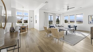 Amplia sala de estar con comedor, ventanas grandes y ventilador de techo.