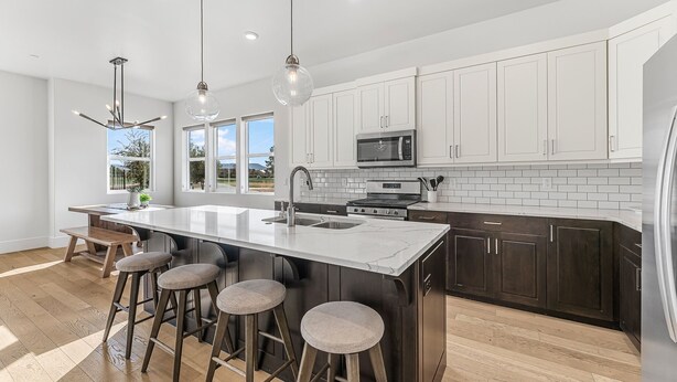 A modern kitchen with a large island, dark wooden cabinets, white countertops, and pendant lighting. - Villa #07 At Bloomington Country Club 3 Bedroom Condo (St. George)