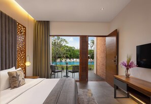 A modern hotel room with a bed, a TV, a wooden bench, and a view of a swimming pool. - Hotel Ferola (Matara)