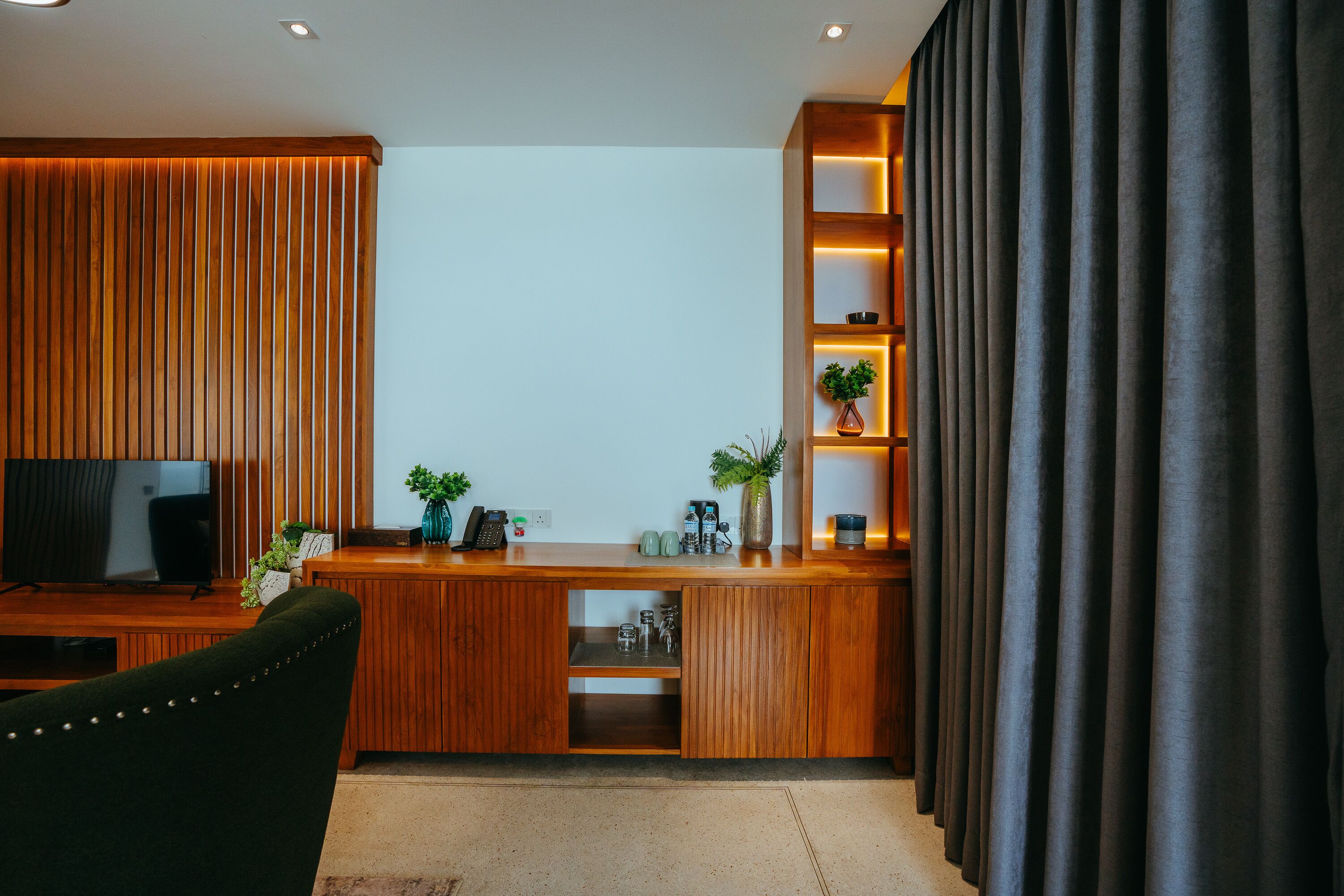 A modern living room with a wooden desk, a television, and a comfortable chair.