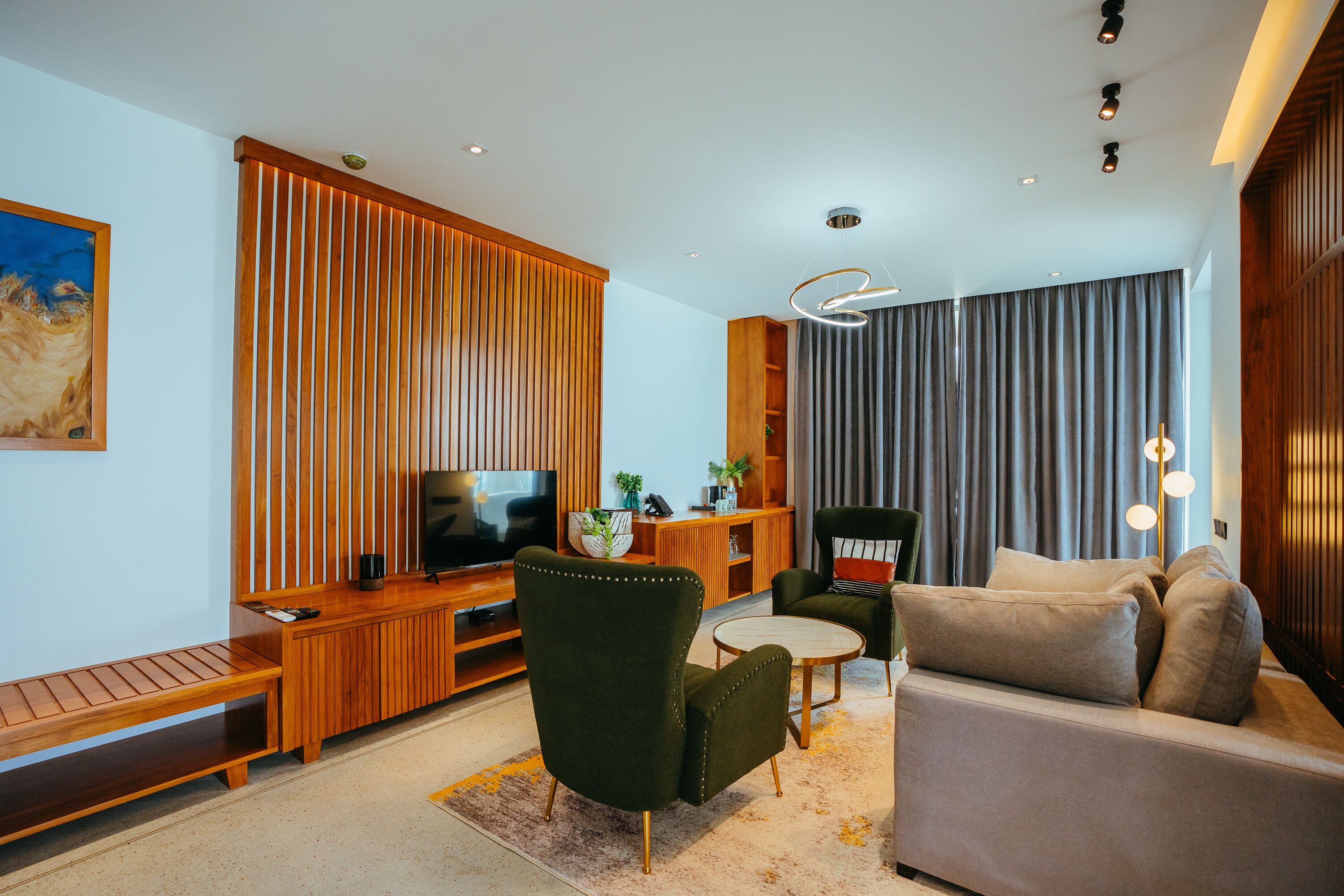 A modern living room with a wooden entertainment unit, a sofa, a green armchair, and a TV.
