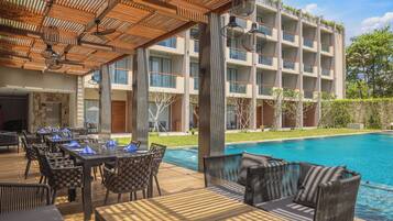 A poolside area with outdoor seating, a pool, and a building with multiple balconies.