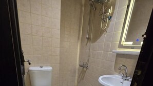 Un baño pequeño con inodoro, ducha y lavamanos.