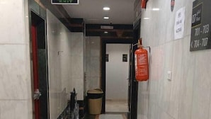Un pasillo con suelo de baldosas, un extintor a la derecha y un cubo de basura en el centro.
