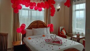 Une chambre d’hôtel avec un grand lit, une tête de lit en bois et des ballons rouges.