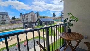 Un balcon donnant sur une piscine, une petite maison et les bâtiments environnants.