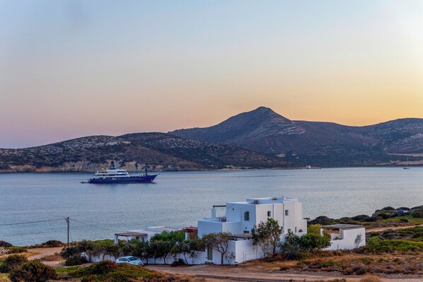 A coastal scene with a ferry, white buildings, and a mountain in the background.