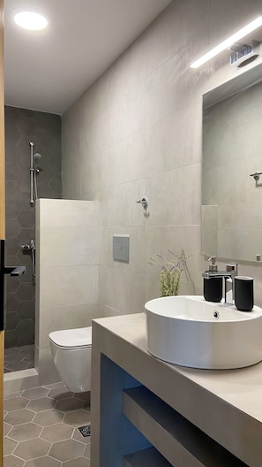 A modern bathroom with a toilet, shower, and sink.