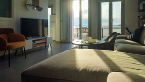 Una sala de estar moderna con un sofá, televisión, una mesa de centro y un balcón con vistas.