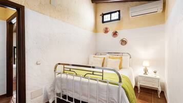 A bedroom with a metal bed frame, a bedside table with a lamp, and a small window.