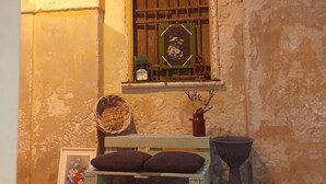 A rustic room with a window, a woven basket, a vase with dried flowers, and a small table with cushions. - baja delle sirene (Taranto)