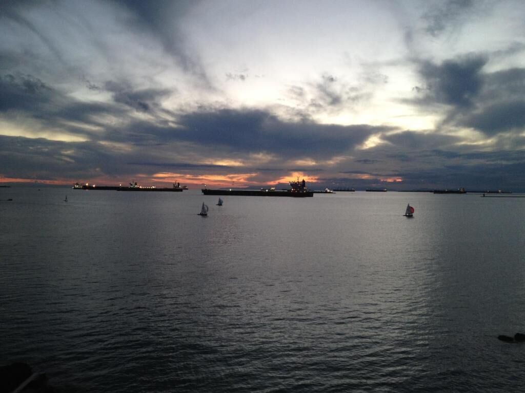 Mar tranquila con un atardecer al fondo y un barco a lo lejos.