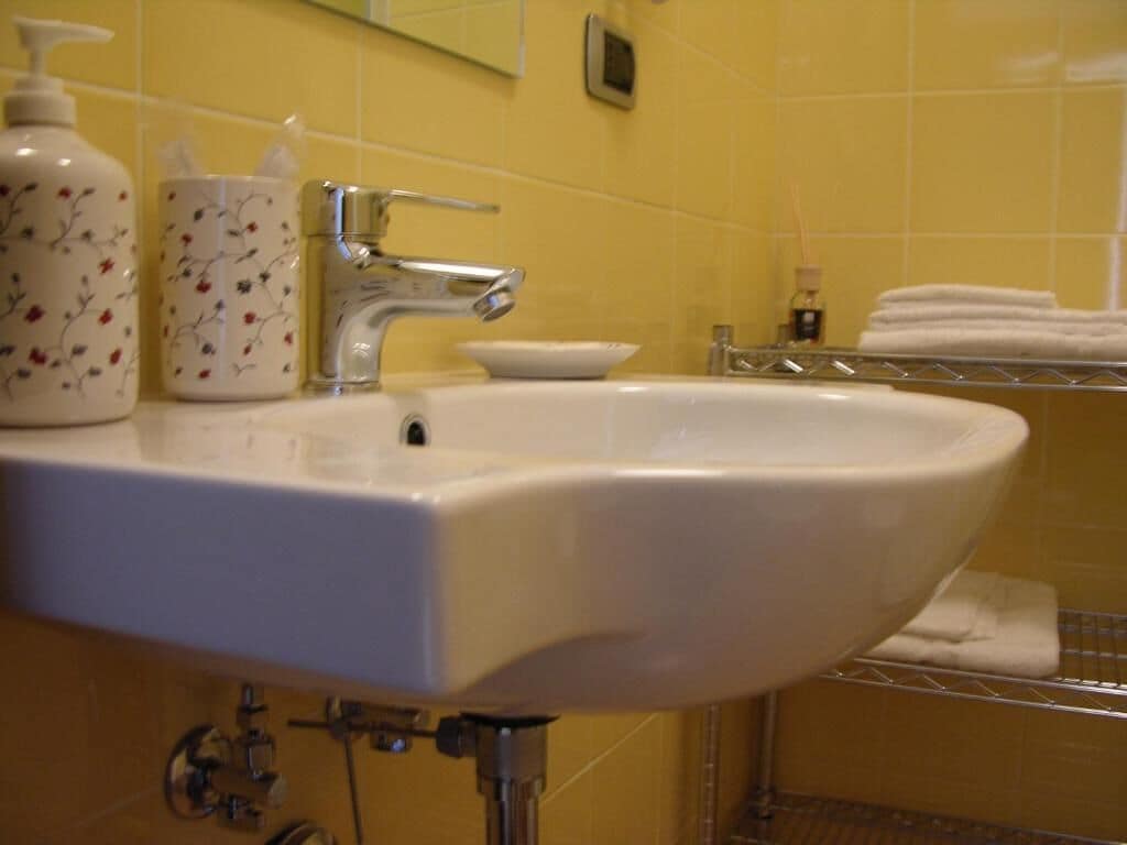 A bathroom sink with a faucet, a soap dispenser, and a cup with floral designs.